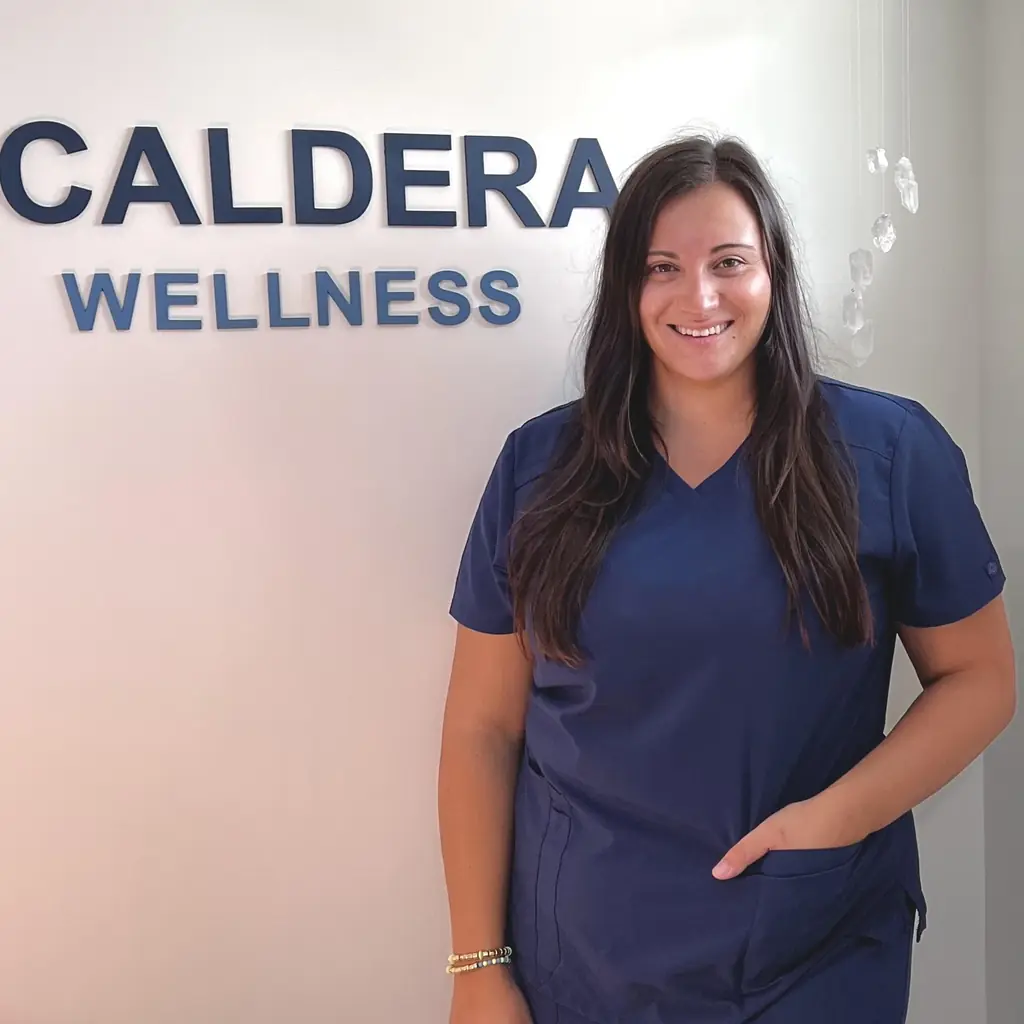 Brianna Del Vecchio standing beside the Caldera Wellness sign in the studio