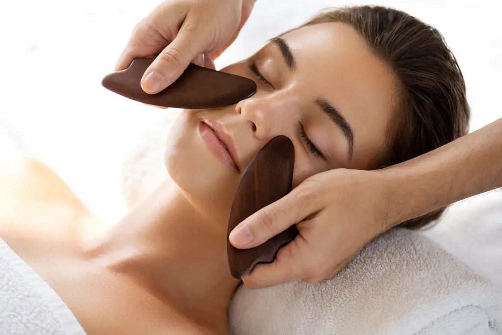 An esthetician using smooth wooden tools during a facial treatment