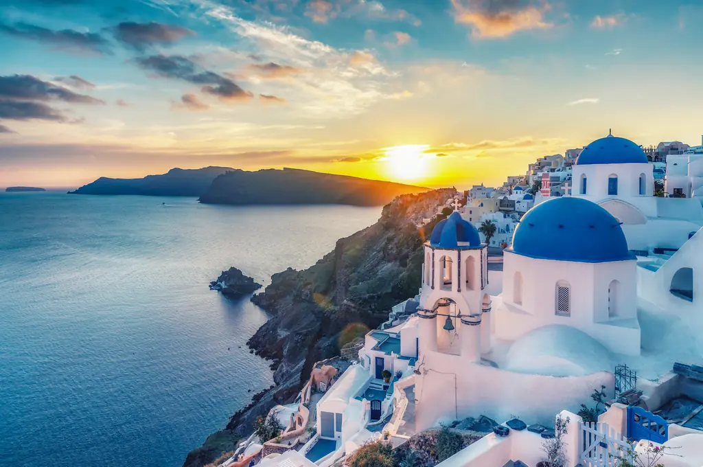Whitewashed buildings and blue domes of Santorini overlooking the caldera at sunset
